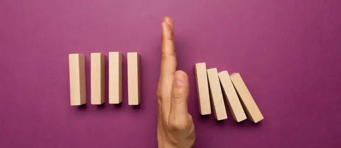 Hand stopping domino reaction.