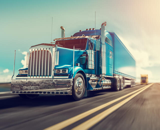 A blue semi-truck is on the road.