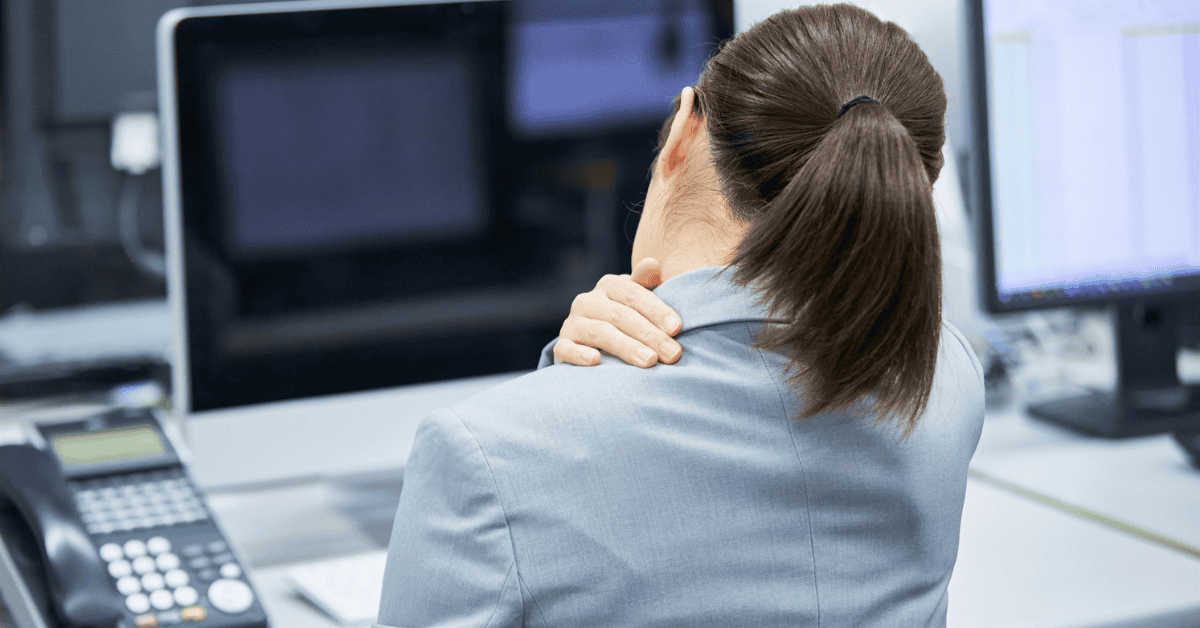 Woman at her work desk, experiencing delayed pain from an automobile accident