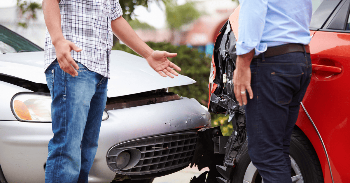 Drivers examining damage after a car accident in Arkansas, discussing the collision.